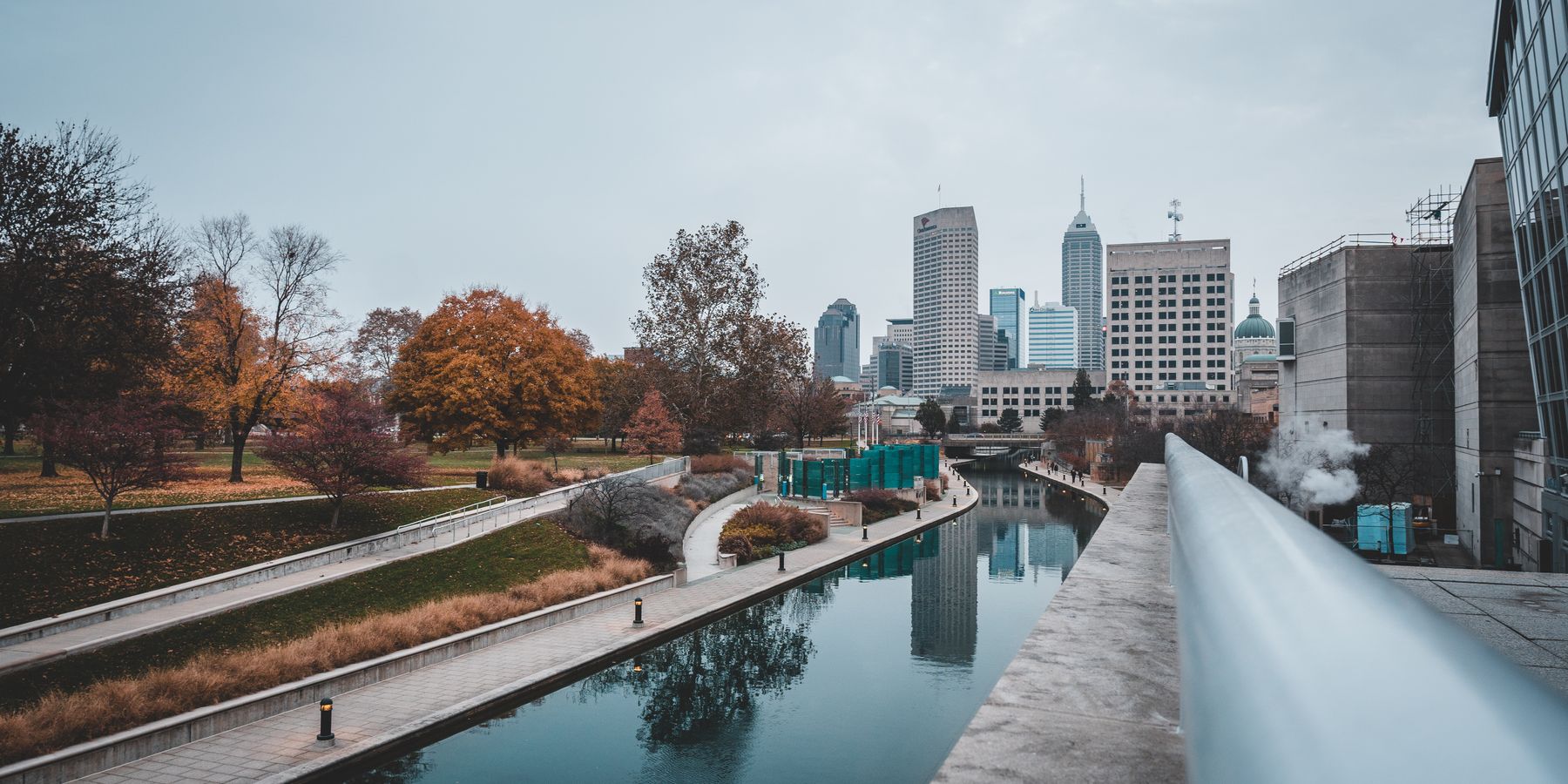 Scenic view of Indianapolis canal with city skyline and autumn colors reflecting on the water.