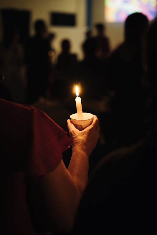 A person holding a candle in front of a crowd