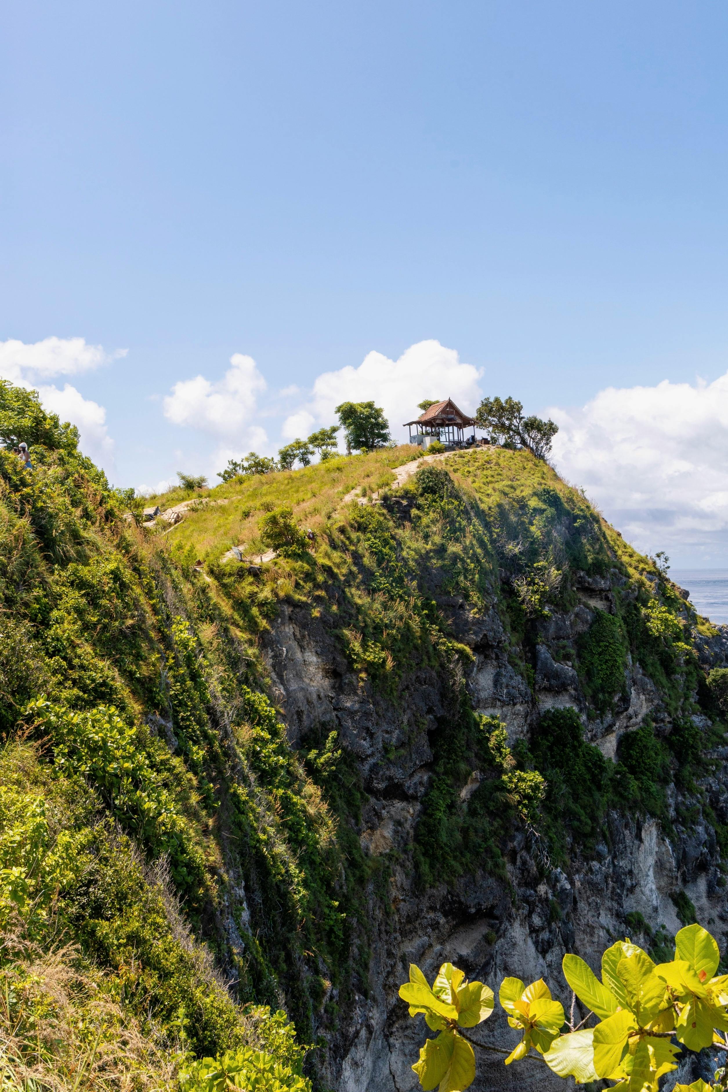 Beautiful landscape of a cliff with greenery under a bright sky, perfect for travel inspiration.