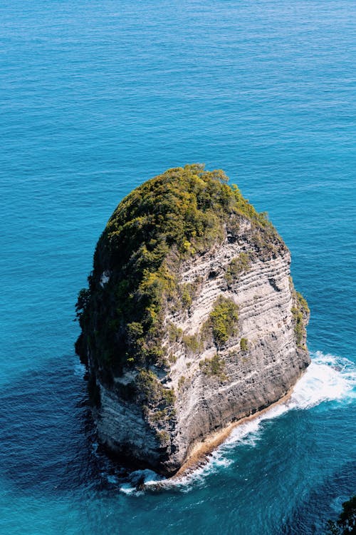 A rock formation in the ocean with blue water