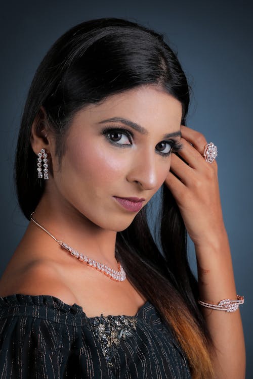 A beautiful young woman posing for a photo wearing a necklace and earrings