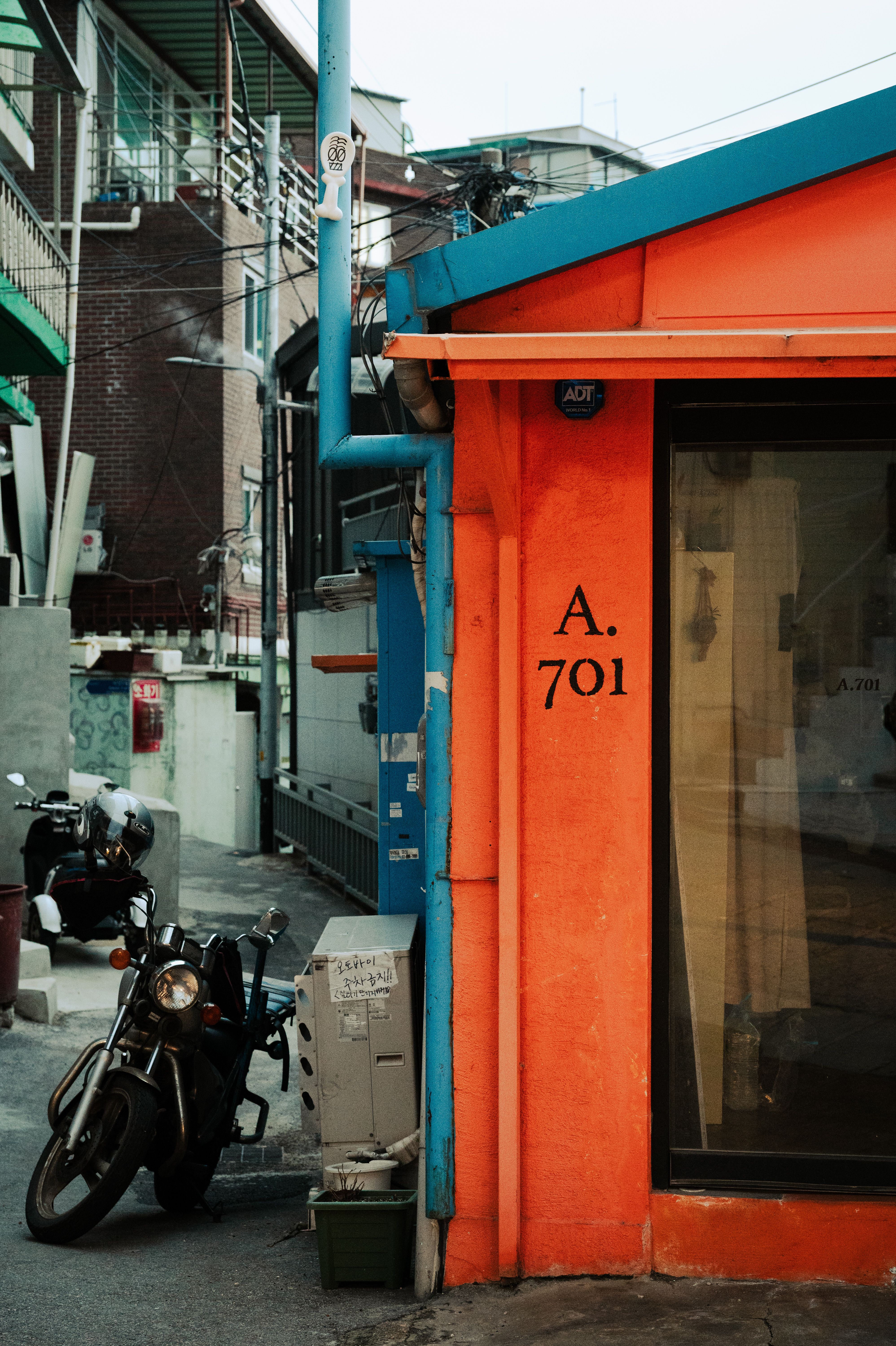 Motorcycle parked in a vibrant alleyway with an orange and blue storefront