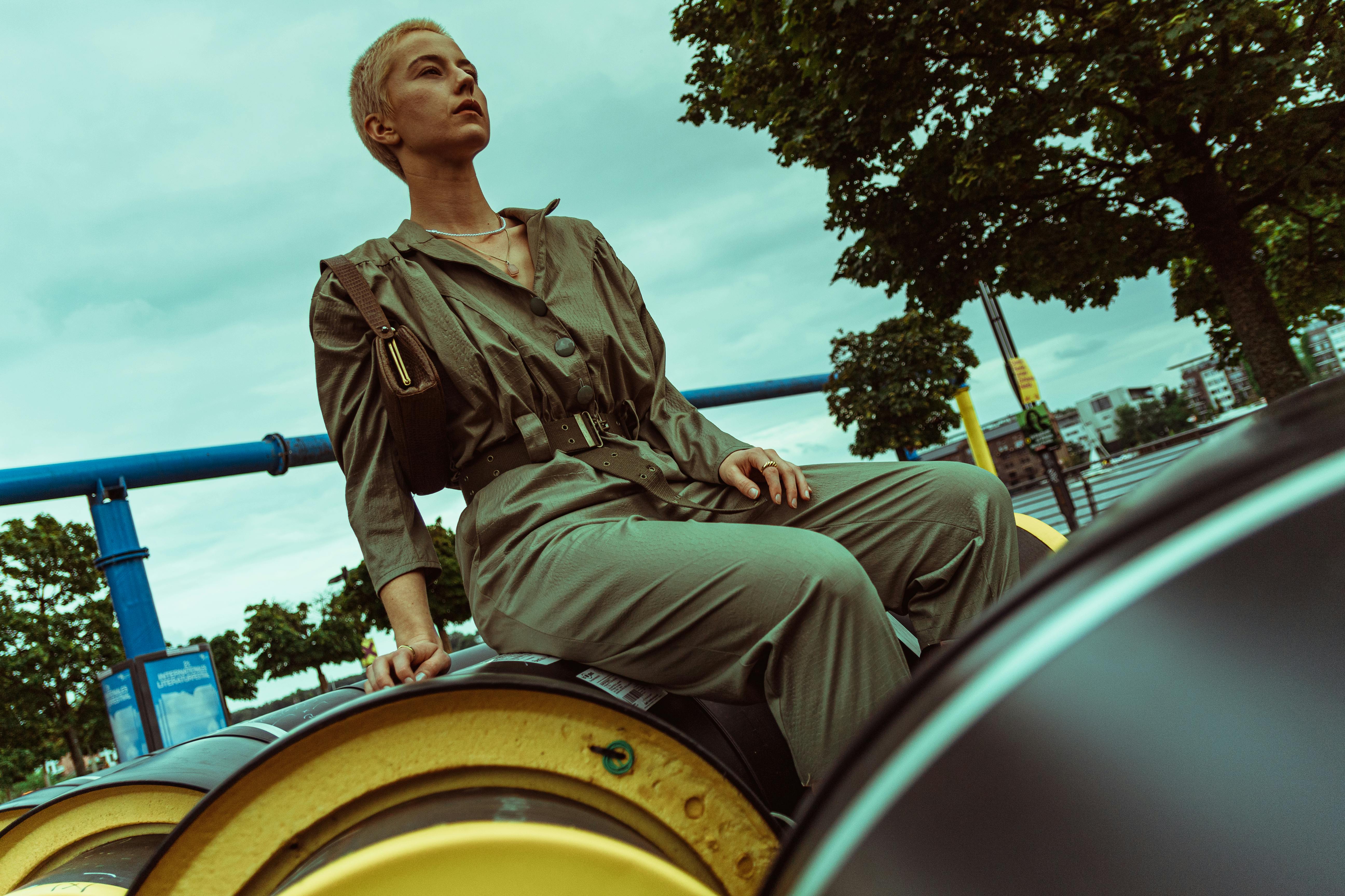 Free Fashion model in a jumpsuit sitting outdoors in Berlin, Germany. Stylish and contemporary. Stock Photo