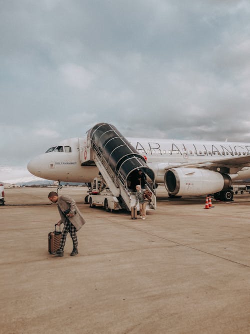 A man is pulling luggage off of an airplane