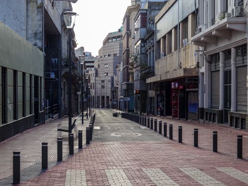 Free Empty street in Montevideo's urban area featuring buildings and bollards on a sunny day. Stock Photo