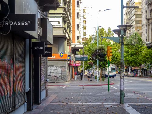 Free Street view of a bustling intersection in Montevideo, Uruguay, featuring shops and greenery. Stock Photo