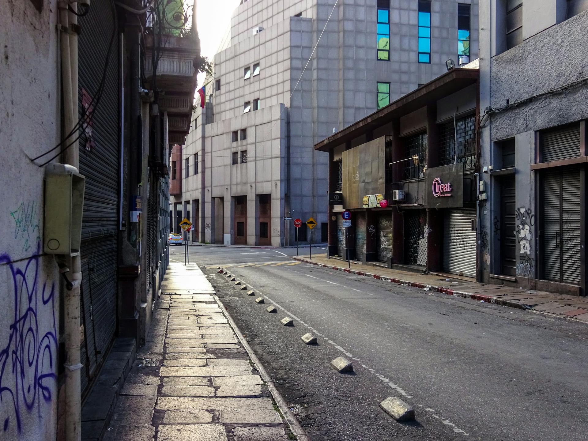 Quiet urban street in Montevideo, Uruguay showcasing closed shops and modern architecture during daytime.