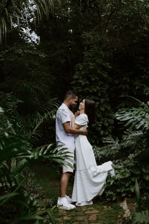 Free Couple in white embracing in a lush jungle setting, symbolizing romance and nature. Stock Photo