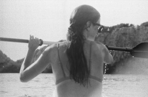 A woman in a bikini paddles a boat