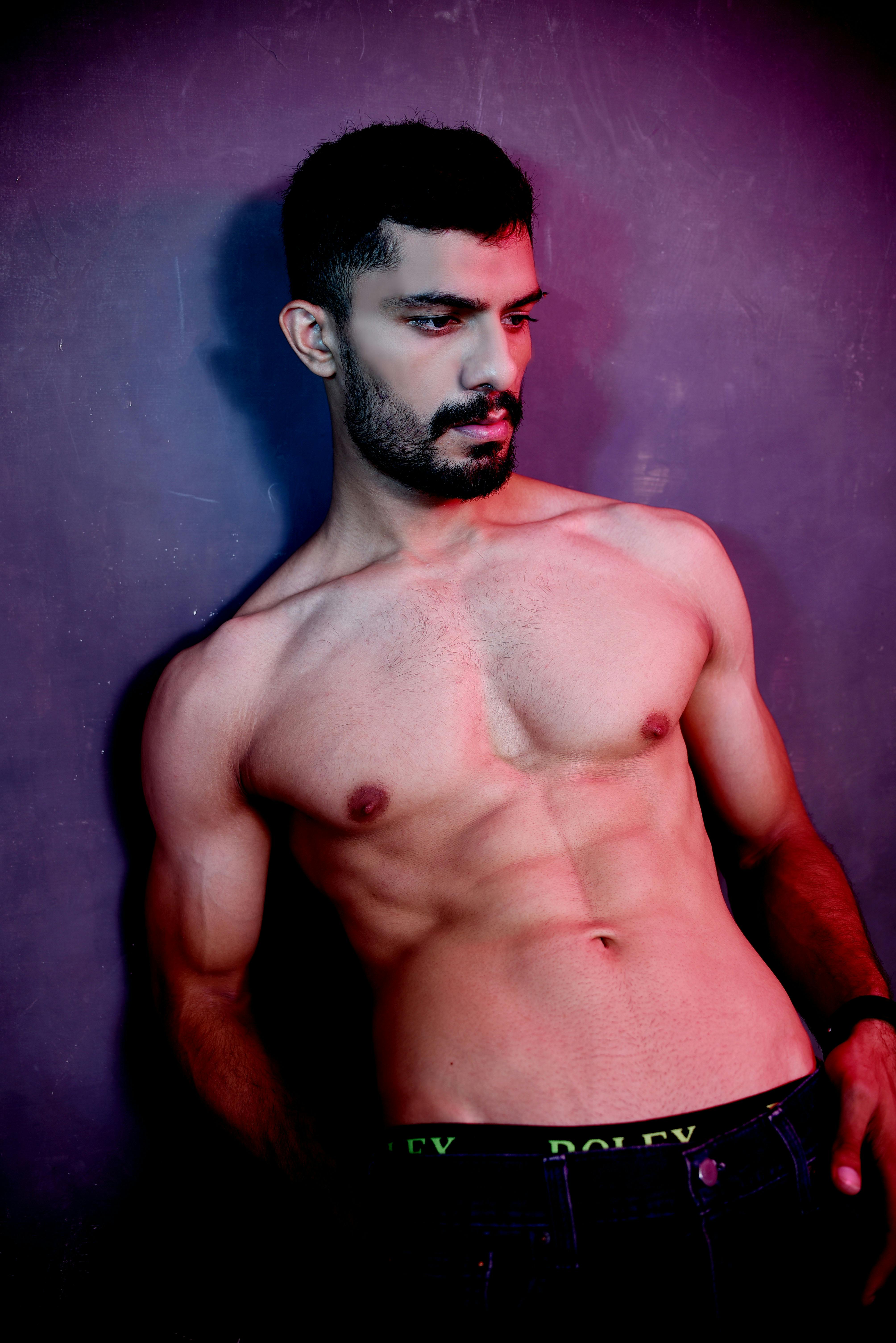 Stylish portrait of a shirtless muscular man posing artistically in studio lighting.