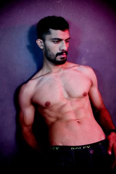 Stylish portrait of a shirtless muscular man posing artistically in studio lighting.