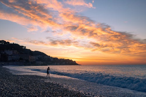 A person walking on the beach at sunset