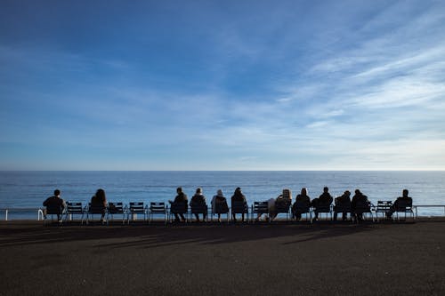 A group of people sitting on chairs on the beach