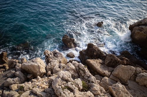 Free A beautiful rocky coastline in Nice, France, with waves crashing against the rocks under bright daylight. Stock Photo