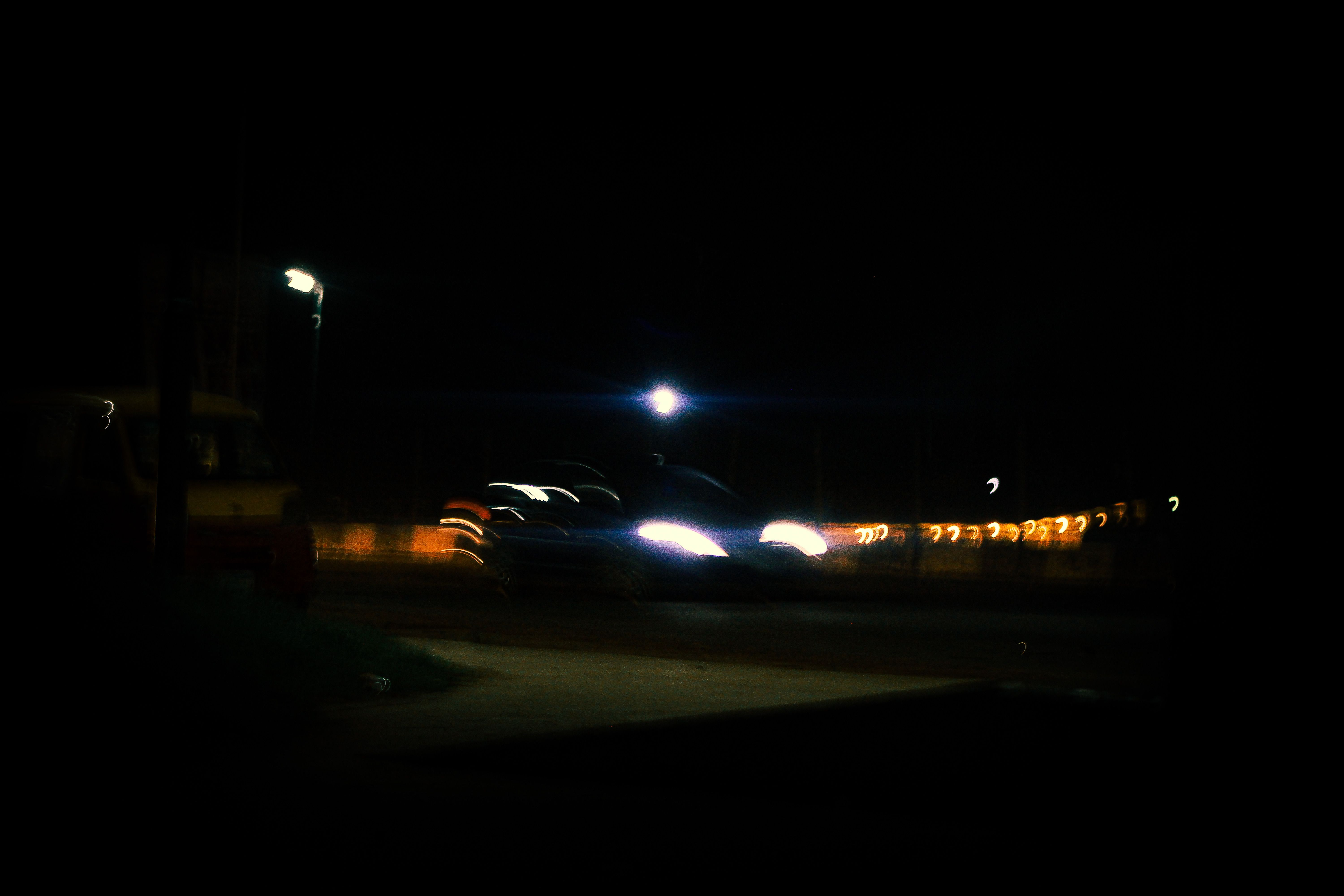 A moody urban night scene with blurred car headlights and street lamps, creating a dynamic atmospher