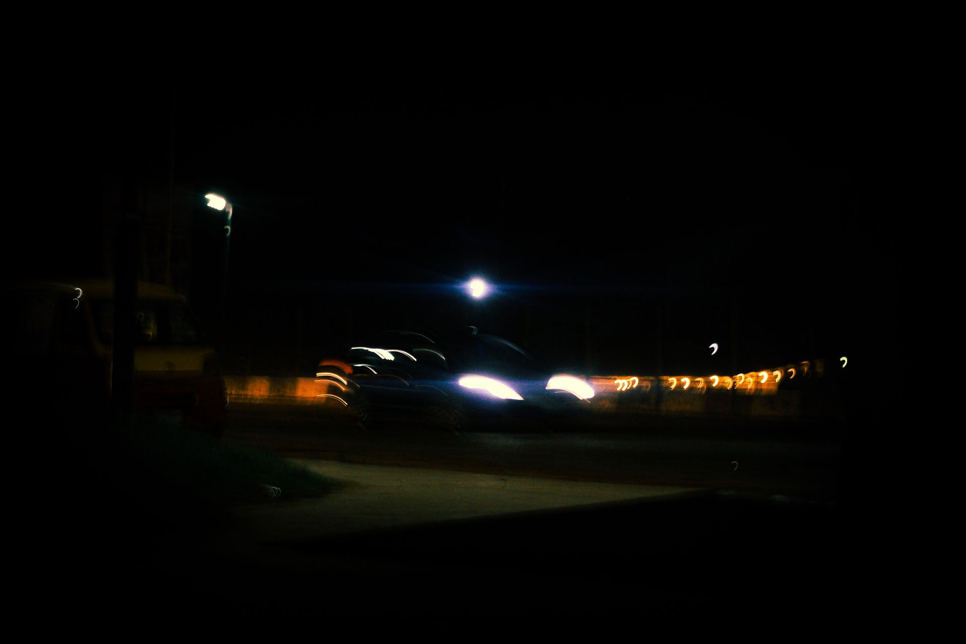 A moody urban night scene with blurred car headlights and street lamps, creating a dynamic atmospher