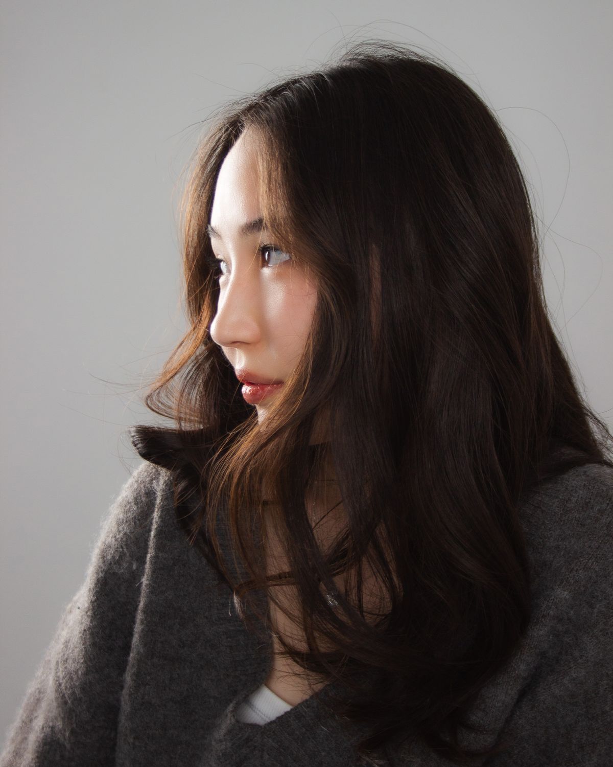 Side profile of Korean hairstyles for women: layered haircut with soft C-curl ends