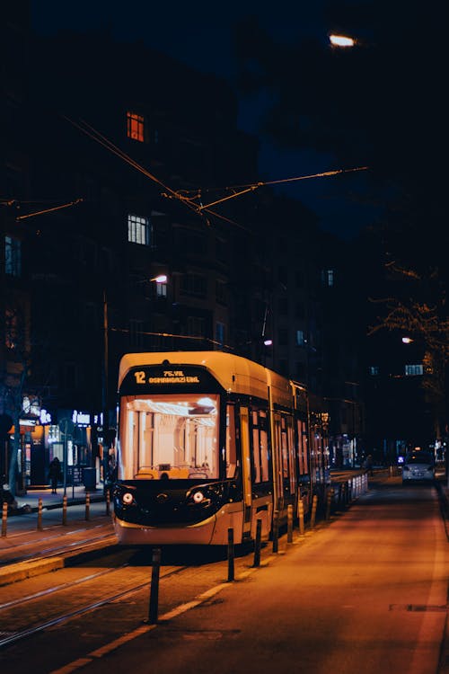A tram is driving down a street at night