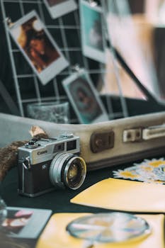 Vintage Canon camera surrounded by Polaroid photos and travel essentials in a cozy setting.