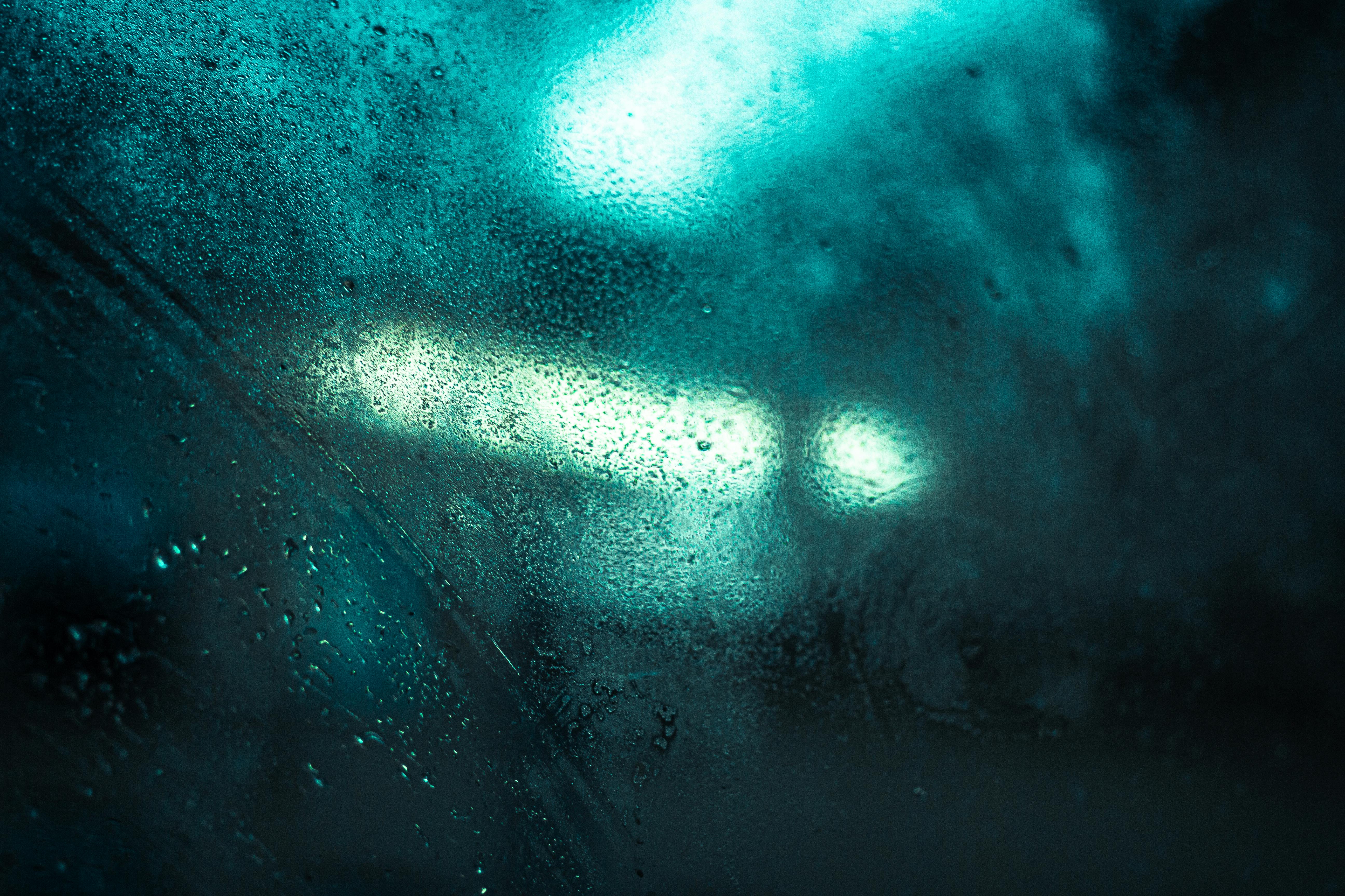 Abstract view of city lights through raindrops on glass, capturing a moody urban ambiance in Edinburgh.