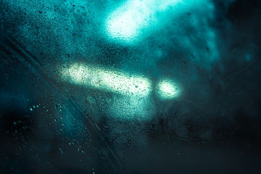 Abstract view of city lights through raindrops on glass, capturing a moody urban ambiance in Edinburgh.