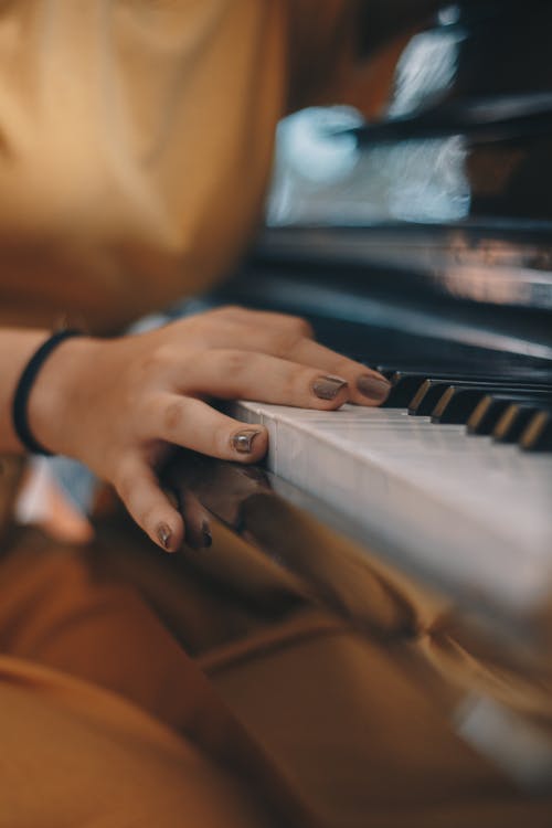 Free Person Wearing Brown Top Holding on Piano Keys Stock Photo