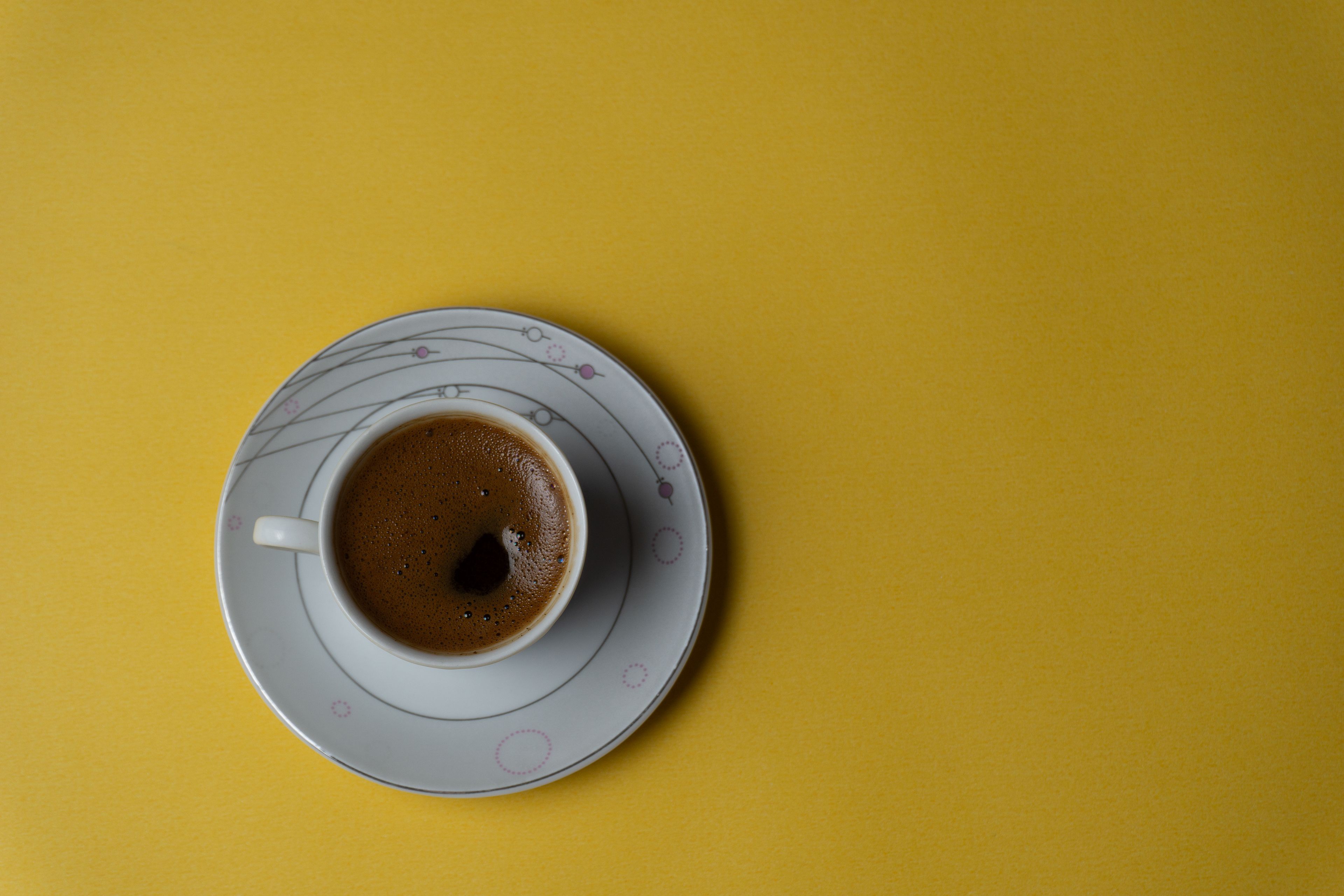 Stylish coffee cup with black coffee on a vibrant yellow background, perfect for modern design.