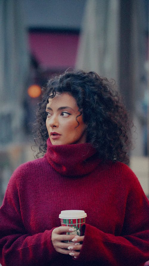 A woman in a red sweater holding a coffee cup