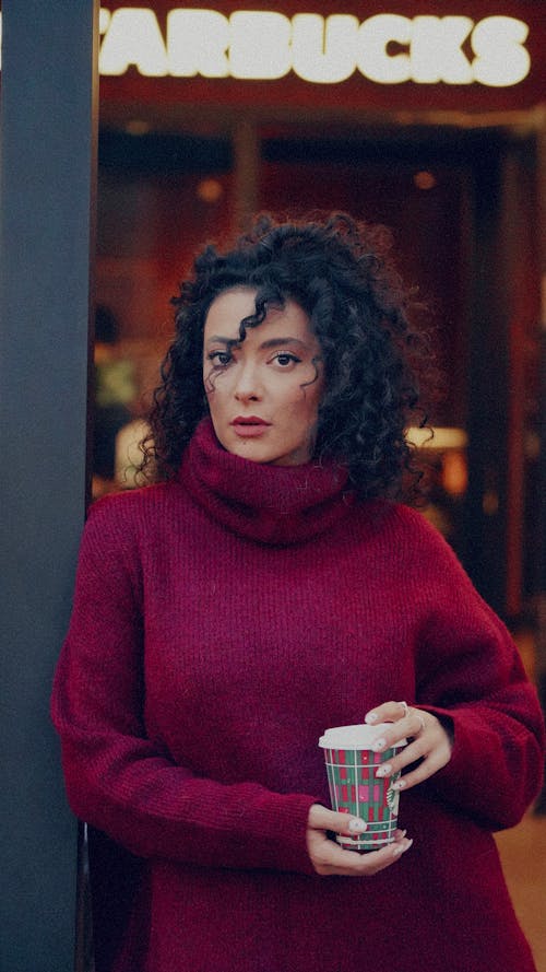 A woman in a red sweater holding a coffee cup