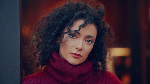 A woman with curly hair wearing a red sweater