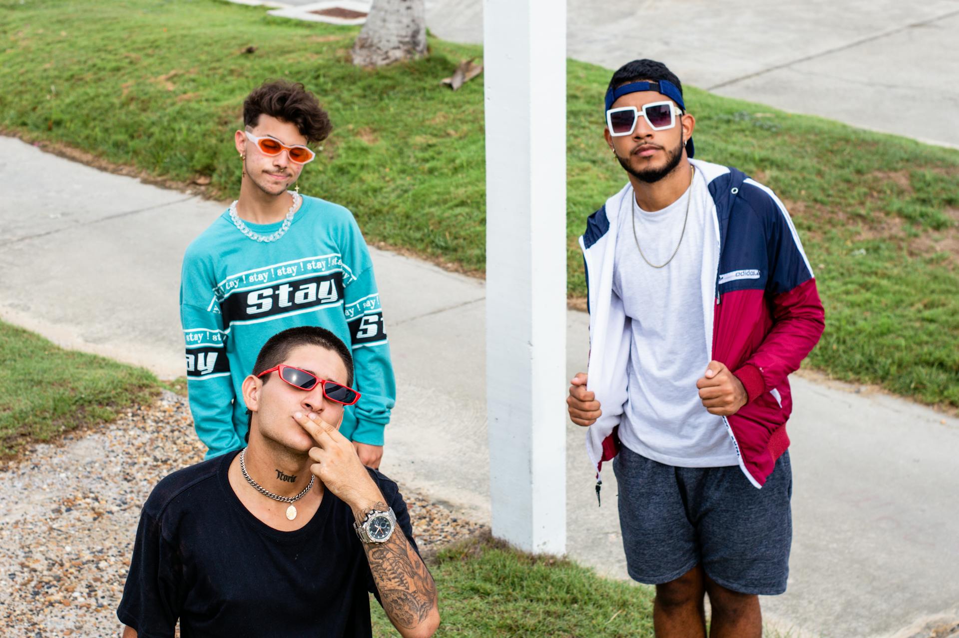 Three stylish young men pose confidently on Cartagena streets, showcasing vibrant and trendy fashion wear.