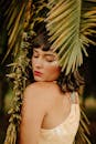 一幅迷人的肖像，描绘了一位闭着眼睛、周围环绕着热带棕榈叶的女子