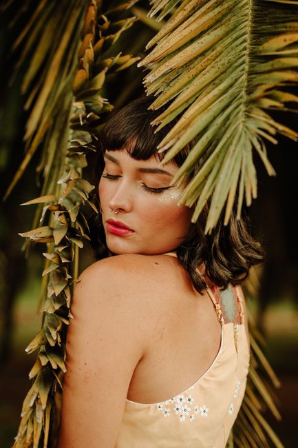 Captivating portrait of a woman with closed eyes surrounded by tropical palm leaves.