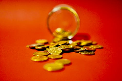 A glass jar filled with coins on a red background