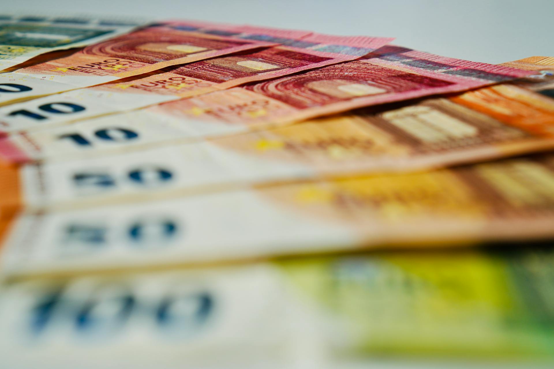 A close-up image of euro banknotes in various denominations spread out, showcasing currency details.