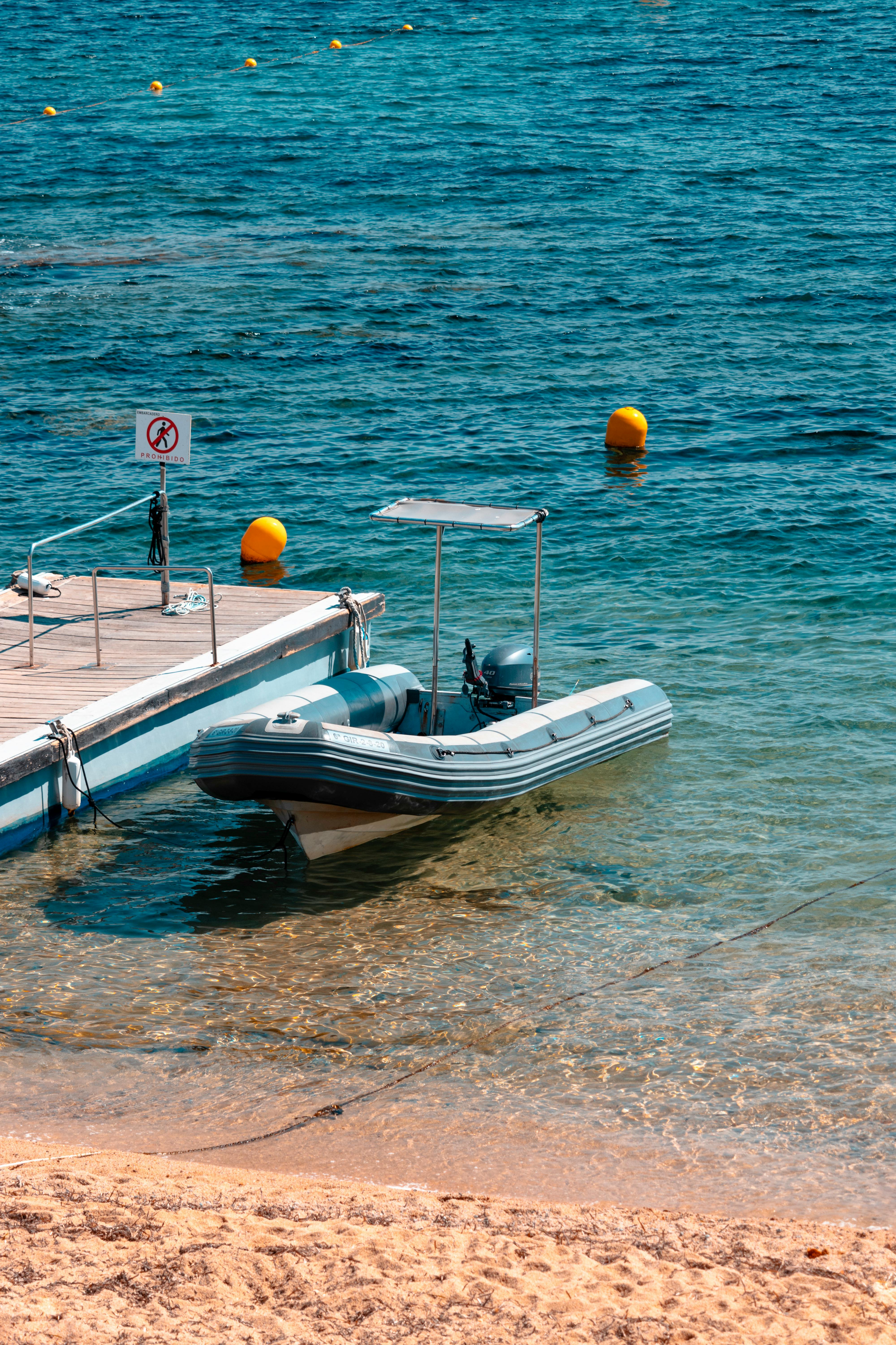 Prescription Goggle Inserts - A peaceful scene of an inflatable motorboat moored to a jetty by the clear sea under bright sunshine.