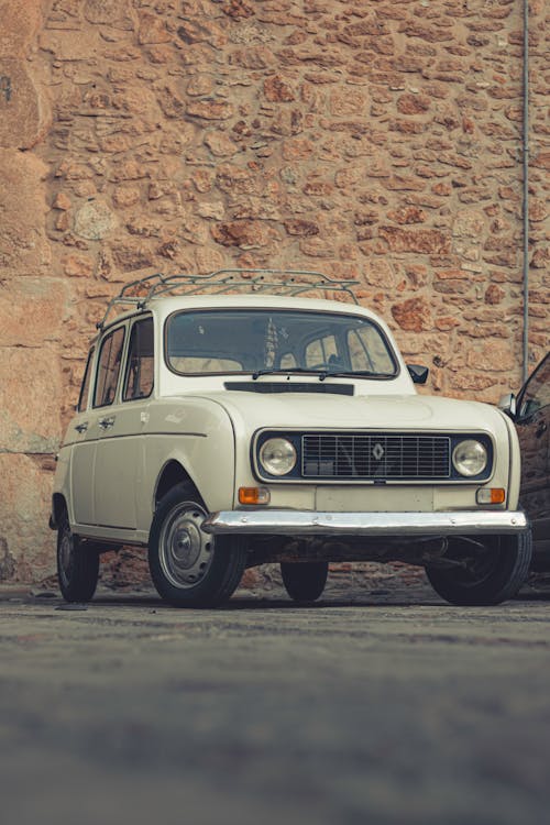 A white car parked in front of a brick wall