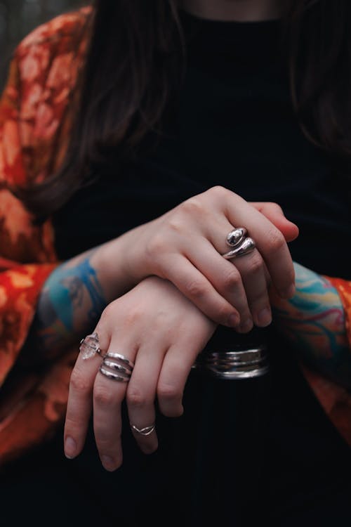A woman with tattoos and rings on her hands