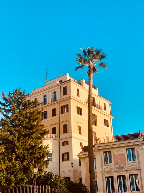 Free A luxurious building with a palm tree against a vibrant blue sky perfect for summer vibes. Stock Photo