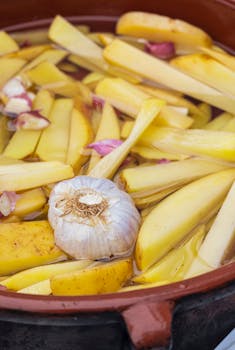 Close-up of potatoes and garlic in a clay pot, perfect for rustic food prep.