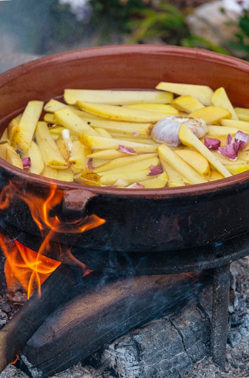 A pot of potatoes cooking on a fire
