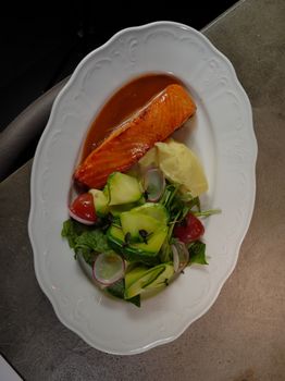 Elegant plated salmon with fresh salad and radishes, ready for dining.