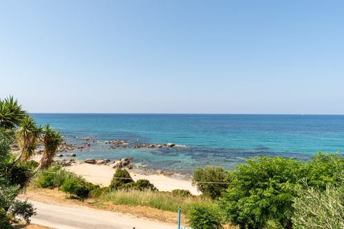 Free A serene beachscape with clear blue waters and vibrant greenery under a bright sunny sky. Stock Photo