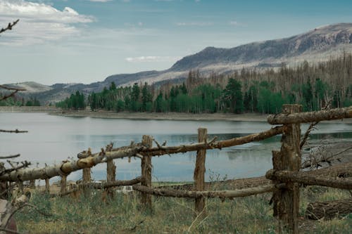 A fence is in front of a lake with mountains in the background