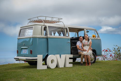 A couple posing for a photo in front of a van with the word love on it