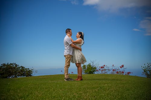 A couple standing on a grassy hill with the ocean in the background