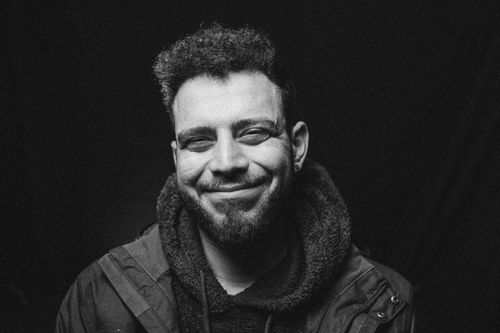 Free Monochrome portrait of a smiling adult man wearing a black hoodie under studio lighting. Stock Photo