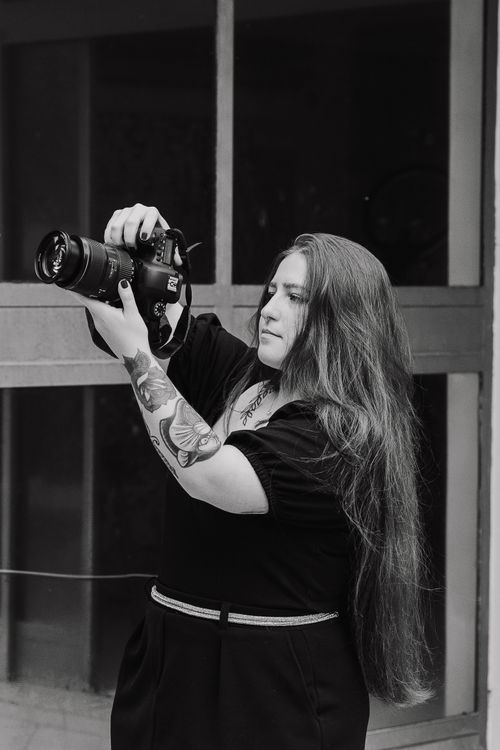 Free Black and white portrait of a woman with long hair taking a photo outdoors. Stock Photo