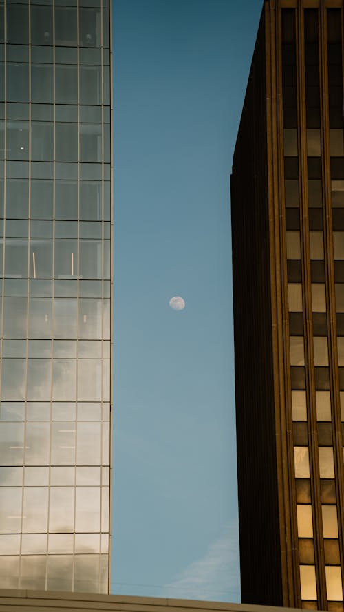 A full moon is seen in the sky above two tall buildings