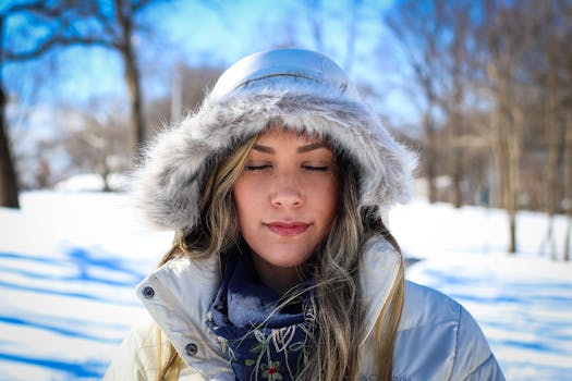 冬日雪景中，一位身着毛皮连帽外套的女子闭目肖像